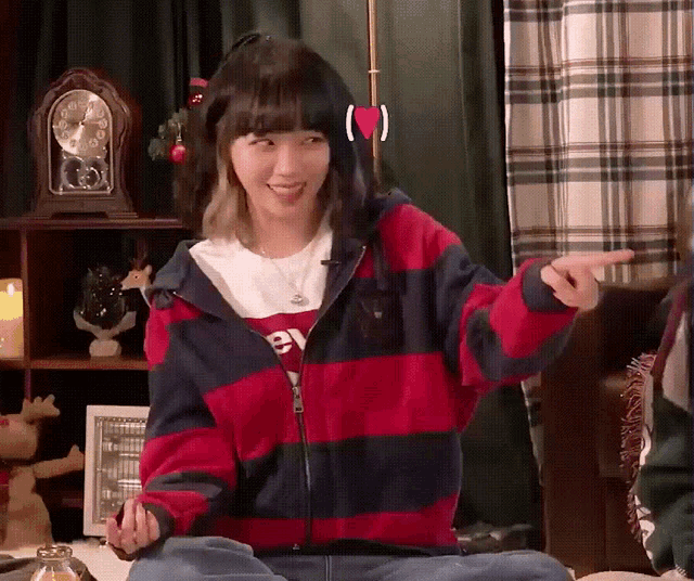 a woman wearing a red and blue striped jacket is pointing