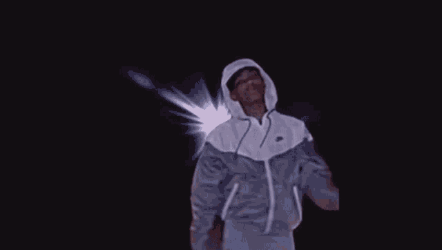 a man in a hoodie is holding a cell phone to his face .