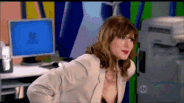 a woman in a suit is standing in front of a computer screen that says windows