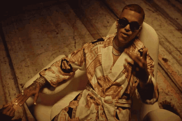 a man in a robe and sunglasses is sitting on a chair