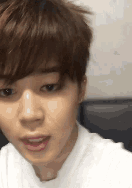 a close up of a person 's face with brown hair and a white shirt