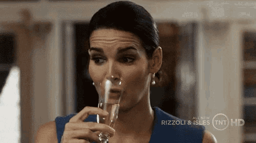 a woman drinking a glass of champagne from rizzoli and isles