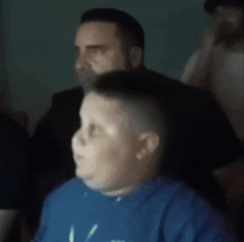 a boy wearing a blue shirt with the letter v on it looks at something