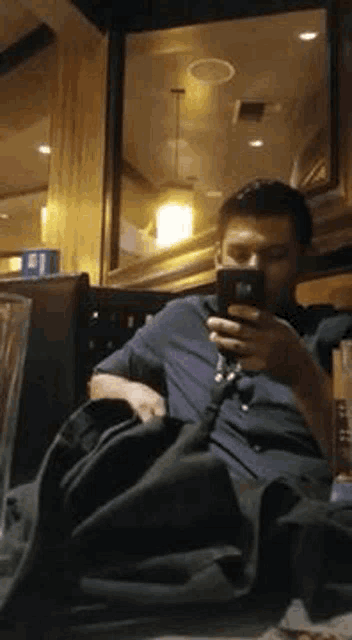 a man is sitting in a chair looking at his phone