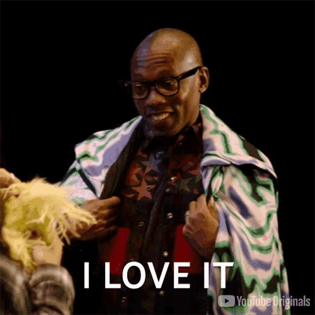 a man wearing glasses and a colorful blanket says " i love it "