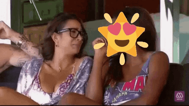 two women are sitting on a couch and one has a star with hearts on her eyes