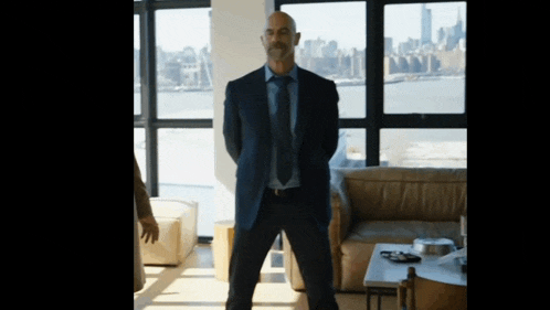 a man in a suit and tie stands in front of a window