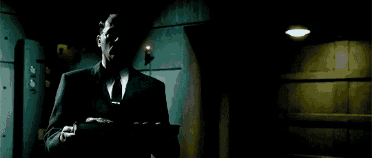 a man in a suit and tie is standing in a dark room .