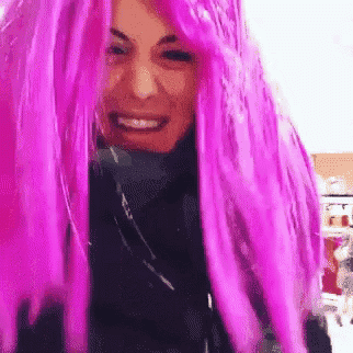 a woman wearing a purple wig is smiling and looking at the camera .