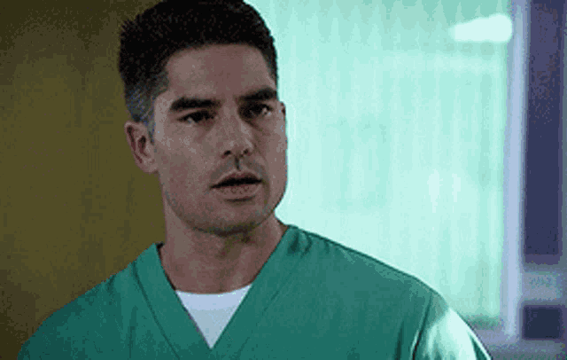 a man is wearing a green scrub top and a white shirt