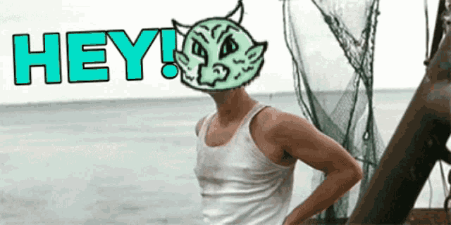 a man in a white tank top is standing in front of the ocean with the word hey written above him