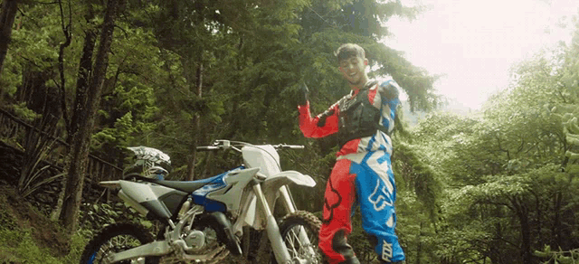 a man standing next to a dirt bike wearing fox pants