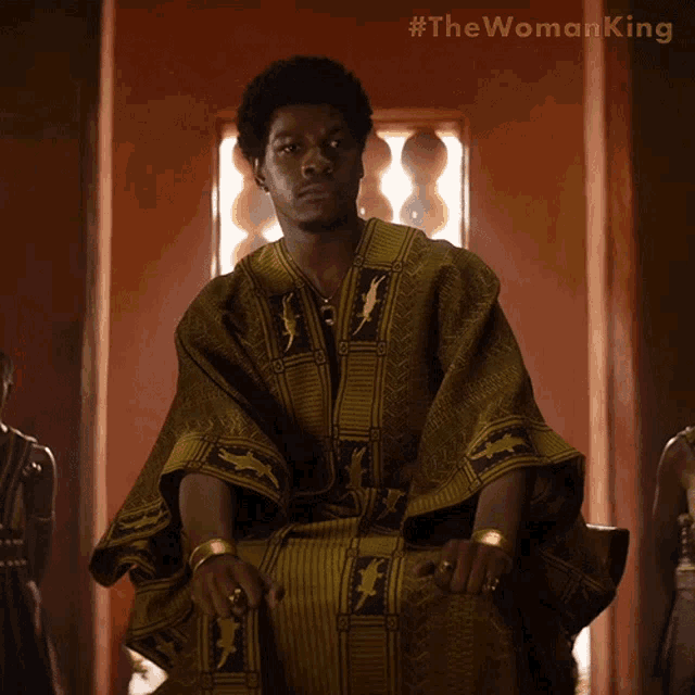 a man is sitting in a chair with #the woman king written on the bottom