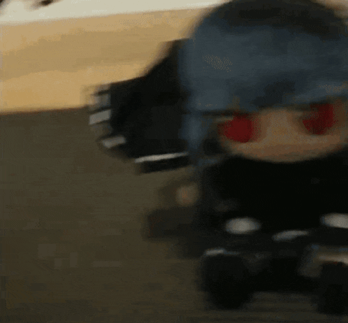 a doll with red eyes and a blue helmet is riding a toy car .