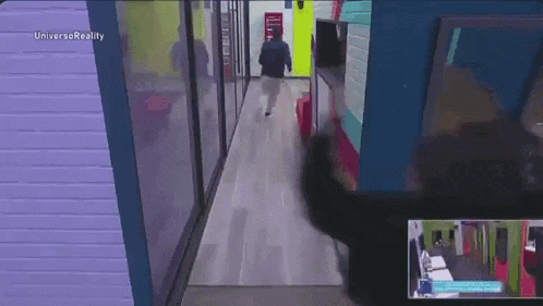 a man is walking down a hallway in front of a television screen .