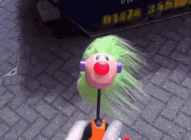 a person is holding a toy that has a green haired face on it