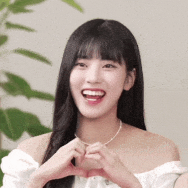 a woman is making a heart shape with her hands and smiling