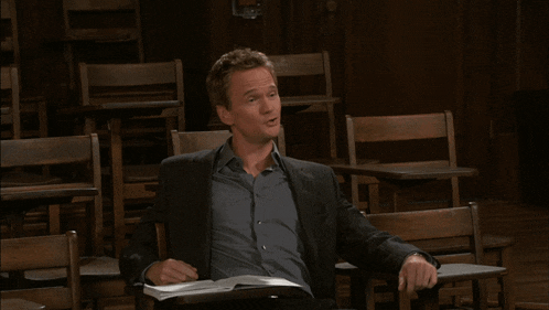 a man in a suit is sitting in a row of wooden chairs