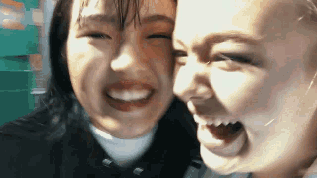 two young women are making funny faces for the camera while standing next to each other .