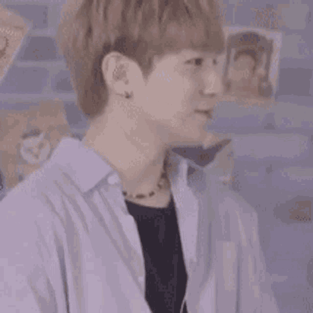 a young man in a purple shirt and black shirt is standing in front of a wall .