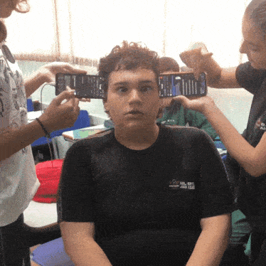 a boy wearing a black shirt that says ' aoc ' on it is being photographed
