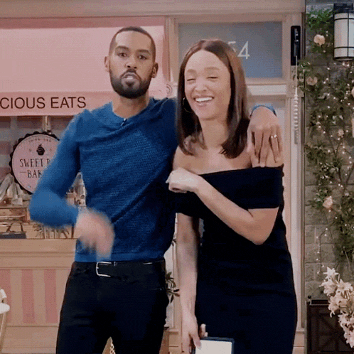 a man and woman are dancing in front of a sign that says " cious eats "