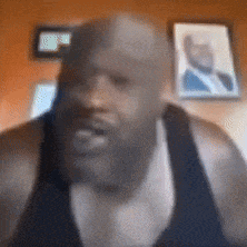 a man with a beard is wearing a black tank top and looking at the camera .