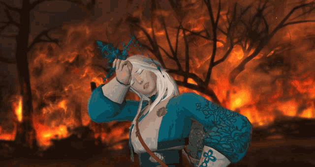 a woman in a blue and white outfit stands in front of a burning forest