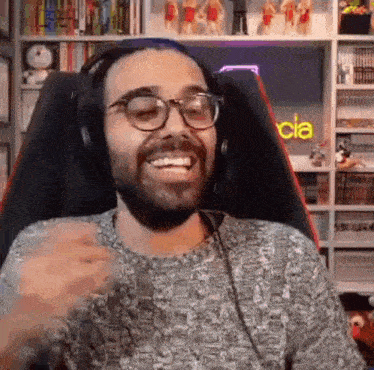 a man with a beard and glasses is wearing headphones and smiling .
