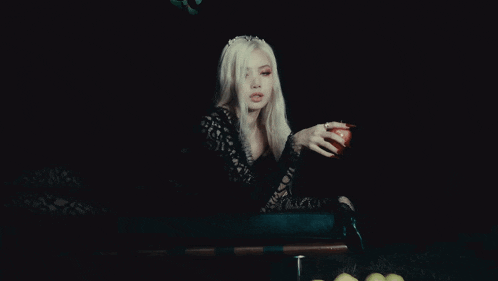 a woman with blonde hair is holding a red apple