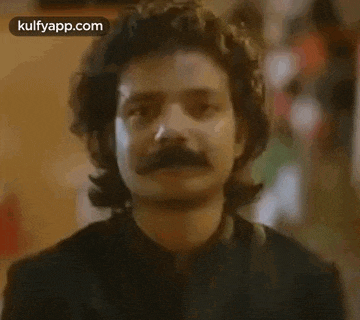 a close up of a man with a mustache and long hair .