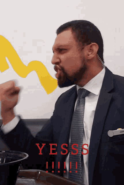 a man in a suit and tie with the word yesss written in red