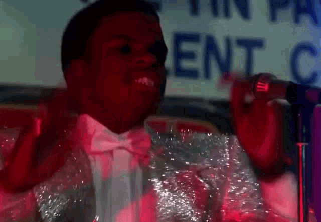a man in a tuxedo is singing into a microphone in front of a sign that says ent