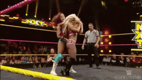 two women are wrestling in a wrestling ring with a referee watching ..