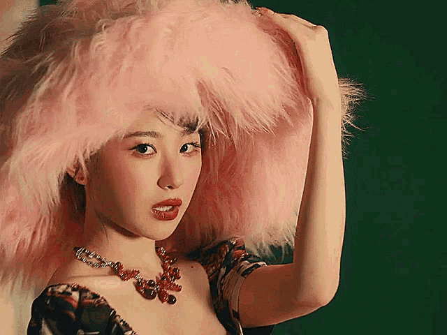 a woman wearing a necklace and a pink fur hat
