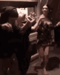 a woman in a dress is dancing with a man in a black hat .