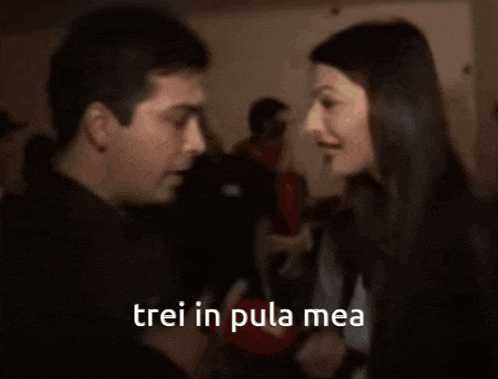 a woman is holding a microphone and talking to a man with the words trei in pula mea above her