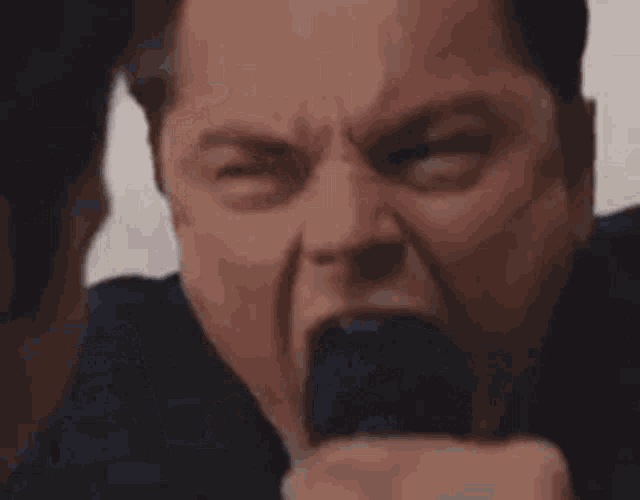 a man in a suit and tie is screaming with his mouth open .