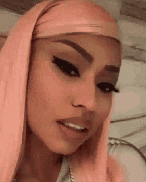 a close up of a woman with pink hair and makeup .
