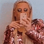 a woman in a pink jacket is taking a selfie with her phone .
