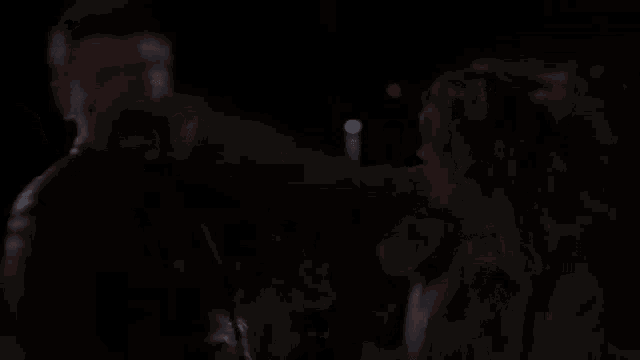 a man and woman are standing next to each other in a dark room .