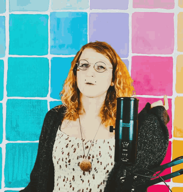 a woman stands in front of a colorful wall holding a microphone that says yamaha