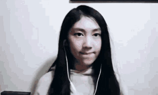 a young girl wearing headphones and a hoodie is making a funny face .