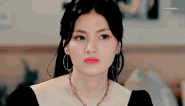 a close up of a woman wearing hoop earrings and a necklace with bubblegum written on the bottom