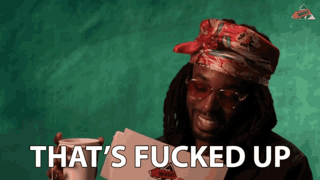 a man with dreadlocks is holding a cup and a piece of paper that says that 's fucked up