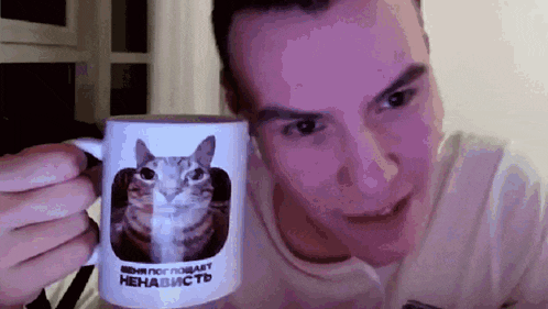 a man is holding up a mug with a cat on it