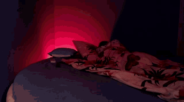 a person is laying on a bed with a floral blanket .
