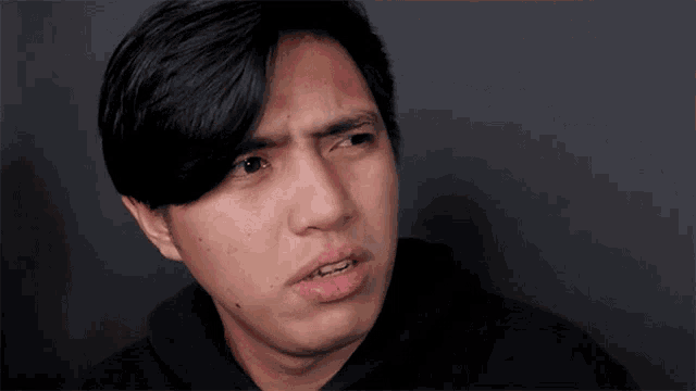 a man in a black hoodie is making a face