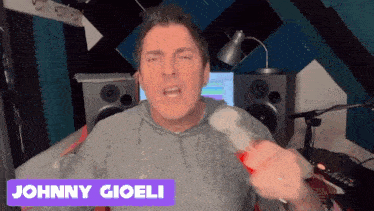 a man in a recording studio with the name johnny gioioli on the bottom