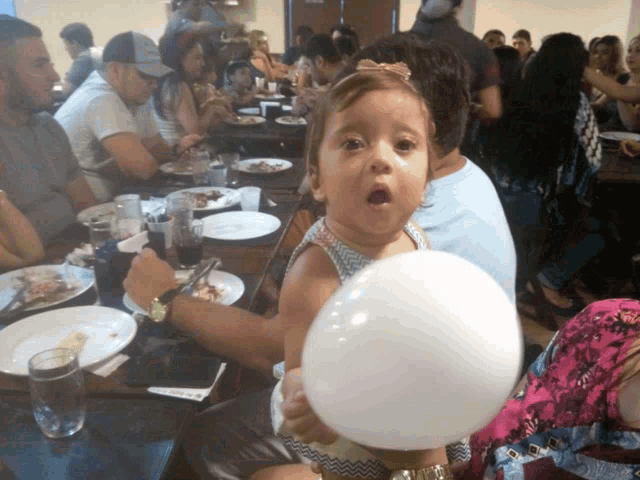 a little girl is holding a white balloon in her hand